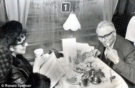 The actor Lord Olivier tucks into eggs and Lady Olivier drinks coffee during a meal onboard a train in 1970